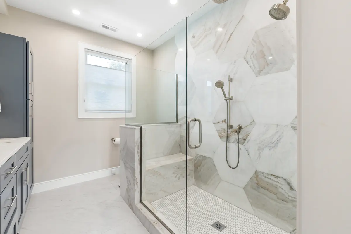 Glass-enclosed shower with hexagonal marble-look tile